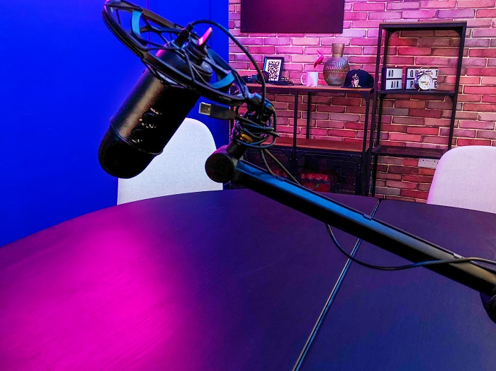 Imagem de uma mesa iluminada com luz roxa, com um pedestal e microfone
