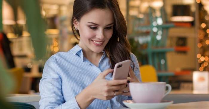 mulher usando celular em uma mesa de café