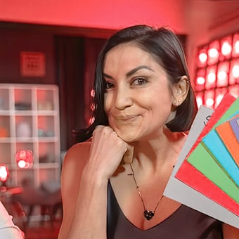 Mulher branca sorrindo segurando leque de papéis.